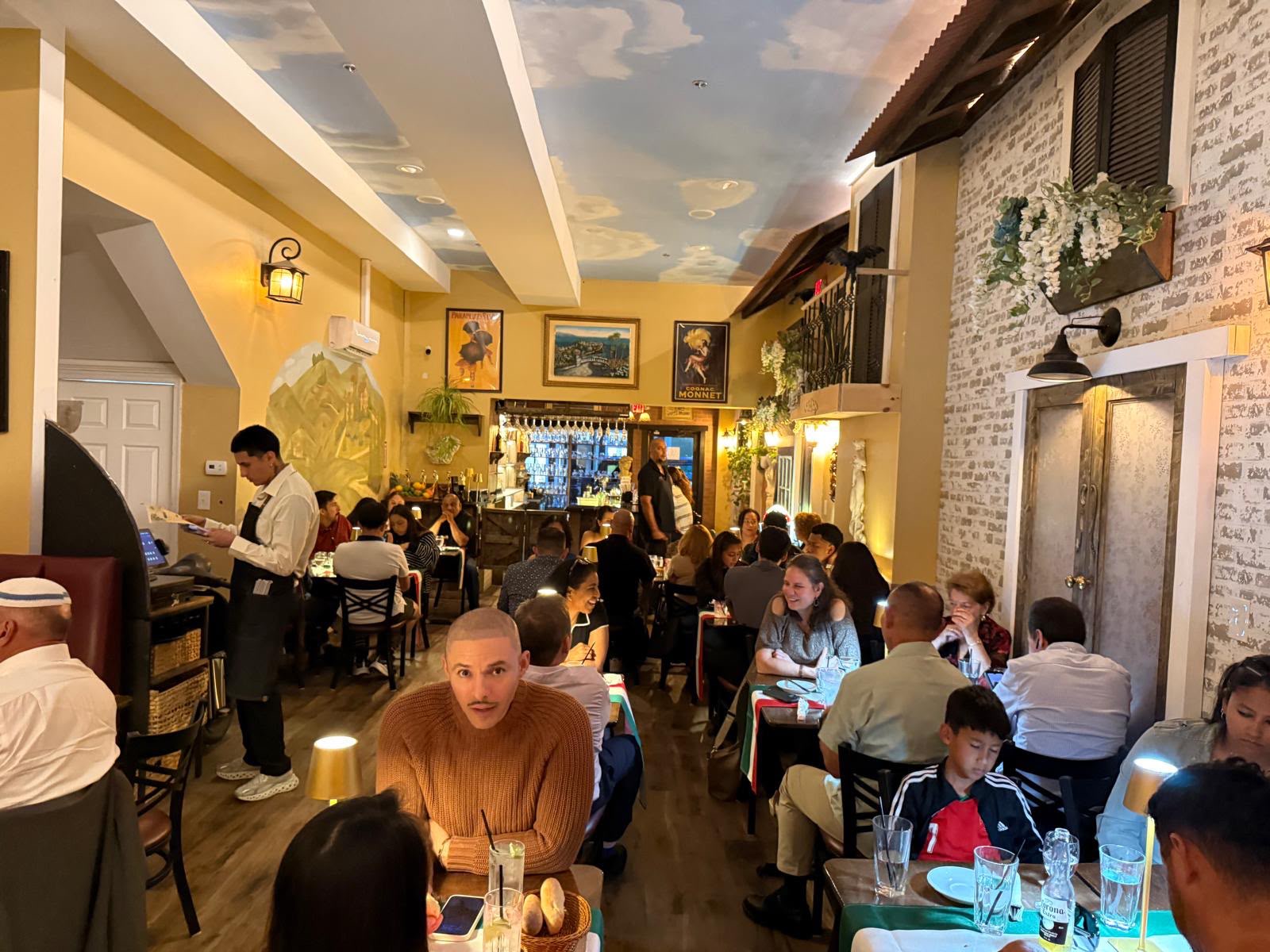 Guests dining inside Villa Italiana, with warm lighting, Italian-inspired decor and the bar in the background