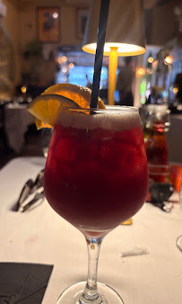 A red drink garnished with orange