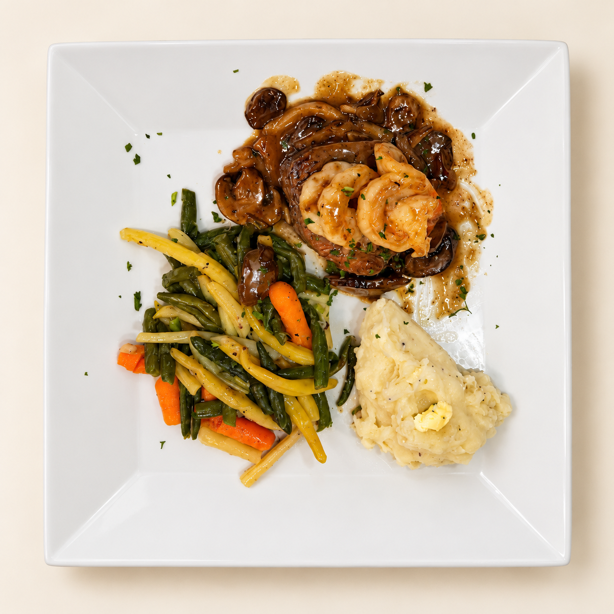 Steak topped with shrimp, served with vegetables and mashed potatoes
