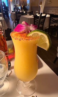 A yellow drink with a lime wedge and an orchid